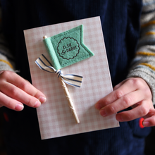 A child is holding a Personalised Father’s Day card with green felt flag reading “Elsie & Daddy”, handmade keepsake card with ribbon and wooden stick detail.