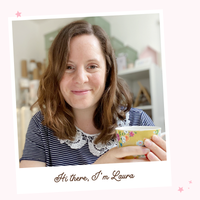 An image of Laura Clempson, the founder of Clara and Macy, wearing a navy blue and white striped top and holding a cup of tea.