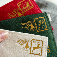 Three handmade felt envelopes, in red, green, and white with golden Christmas stamps and postmarks in the top right corners.