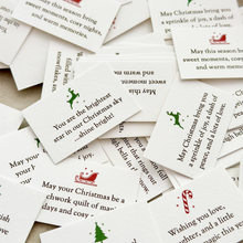 A pile of tiny Christmas wish cards, each with a festive illustration and a written Christmas wish on.