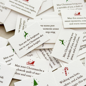 A pile of tiny Christmas wish cards, each with a festive illustration and a written Christmas wish on.