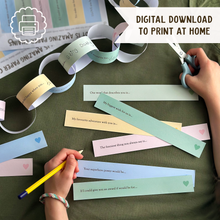 Child completing printable Father's Day paper chain prompts on a green table, creating a colourful Daddy Is Amazing keepsake garland filled with memories and reasons why Dad is loved.