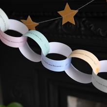 Finished Daddy Is Amazing paper chain garland hanging across a fireplace mantel, filled with handwritten Father's Day memories, compliments and messages from children.