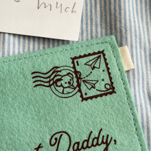 The corner of a handmade green felt envelope with a paper aeroplane stamp and a koala postmark in the top right hand corner.