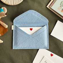 A handmade envelope lays open on dark green fabric. Tucked inside are mini heart notecards, with several written cards beside it. Each written card has a note to Daddy written by children.