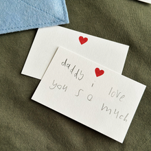Two handwritten notecards lay beside a handmade felt envelope, each with a sweet note to Daddy from children.