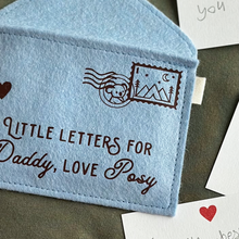The corner of a handmade blue felt envelope with a camping design stamp and a koala postmark in the top right hand corner.
