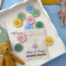 A flat lay of “Mabel & Daddy’s Memory Makers” eco-friendly activity tokens displayed on a white tray, featuring a drawstring cotton bag and colourful wooden discs with bonding prompts like “Go on a nature walk” and “Put some music on and DANCE!”. Ideal for new dads celebrating their first Father’s Day with their baby.