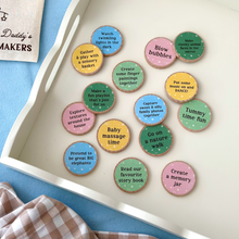 A collection of colourful wooden activity tokens for new dads and babies displayed on a white tray. Each eco-friendly token features bonding prompts such as “Tummy time fun,” “Read our favourite story book,” and “Capture sweet & silly family photos together.” Part of a heartfelt Father's Day gift set designed to inspire memory-making moments between Daddy and baby.