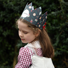 Young girl wearing a festive paper crown with a blurred green background
