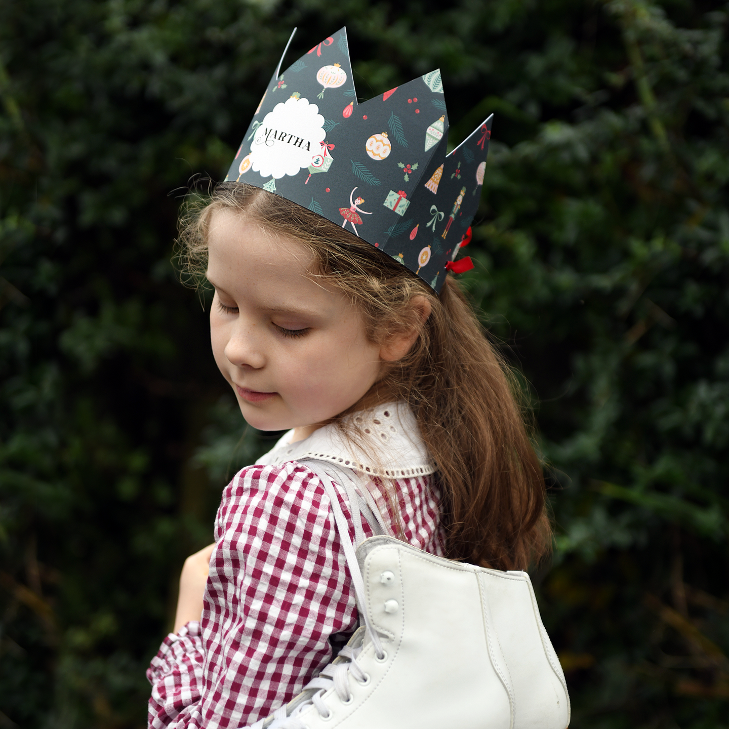 Young girl wearing a festive paper crown with a blurred green background